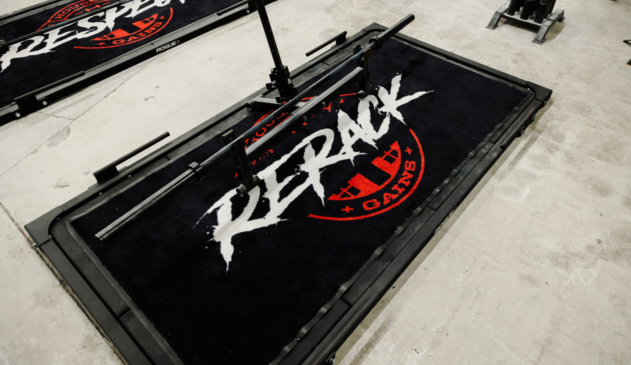 Branded black lifting platforms with red House of Gains badge reading RESPECT and RERACK