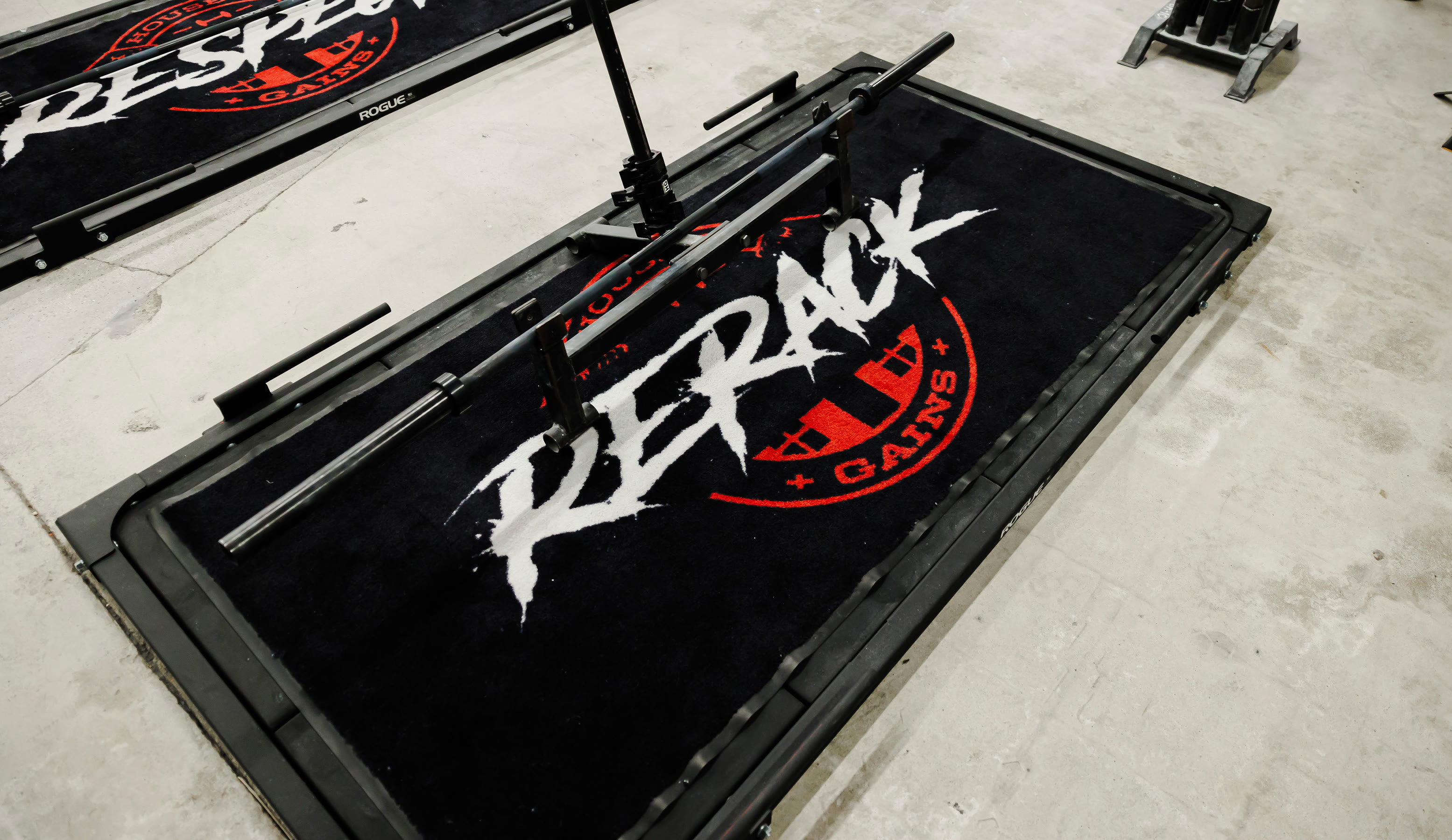 Black platform mat with the red House of Gains badge and the words RESPECT and RERACK painted across it