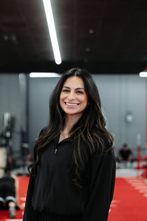 Angela, of the House of Gains Camarillo crew, smiling on the red turf